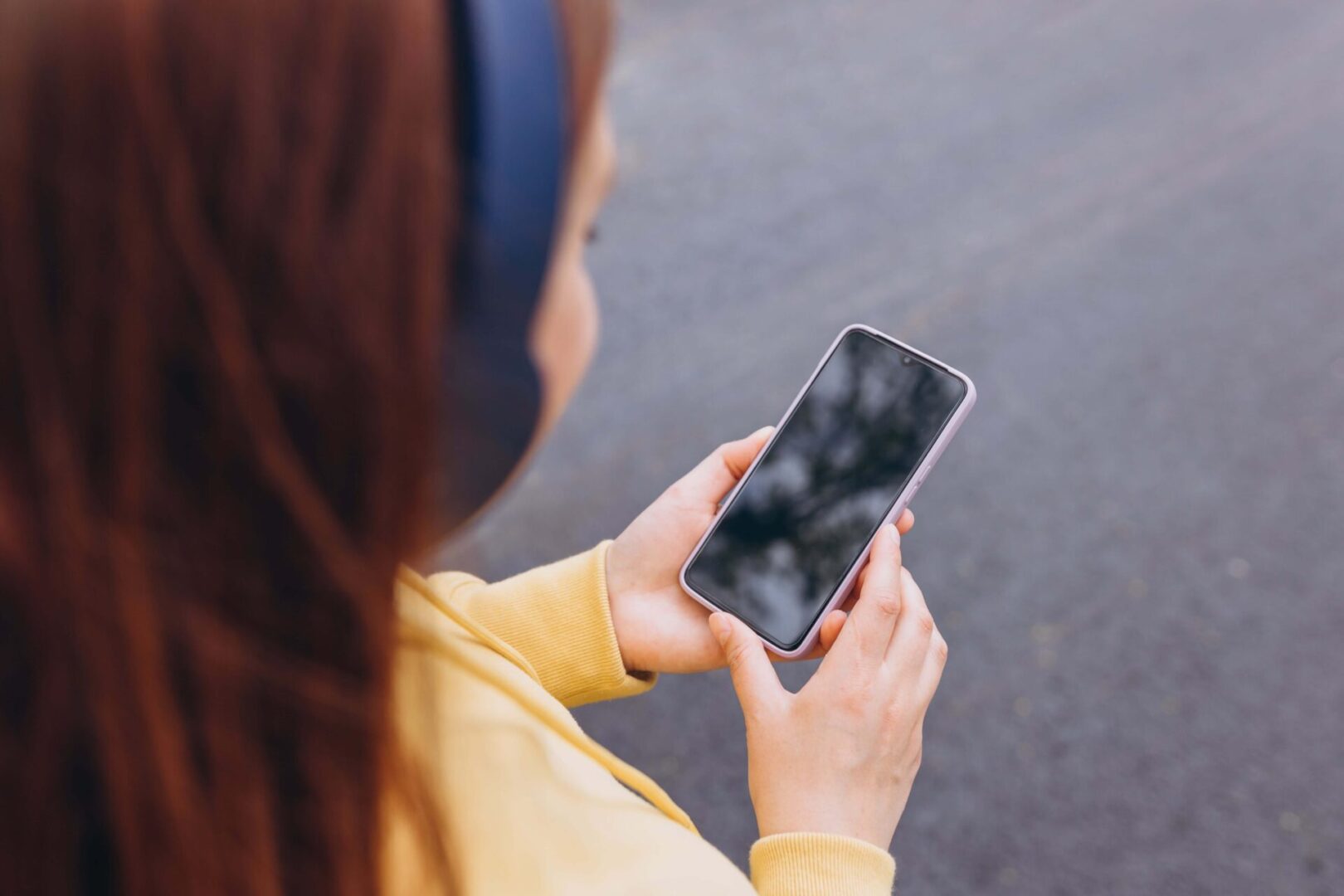 Person holding a smartphone, wearing headphones.
